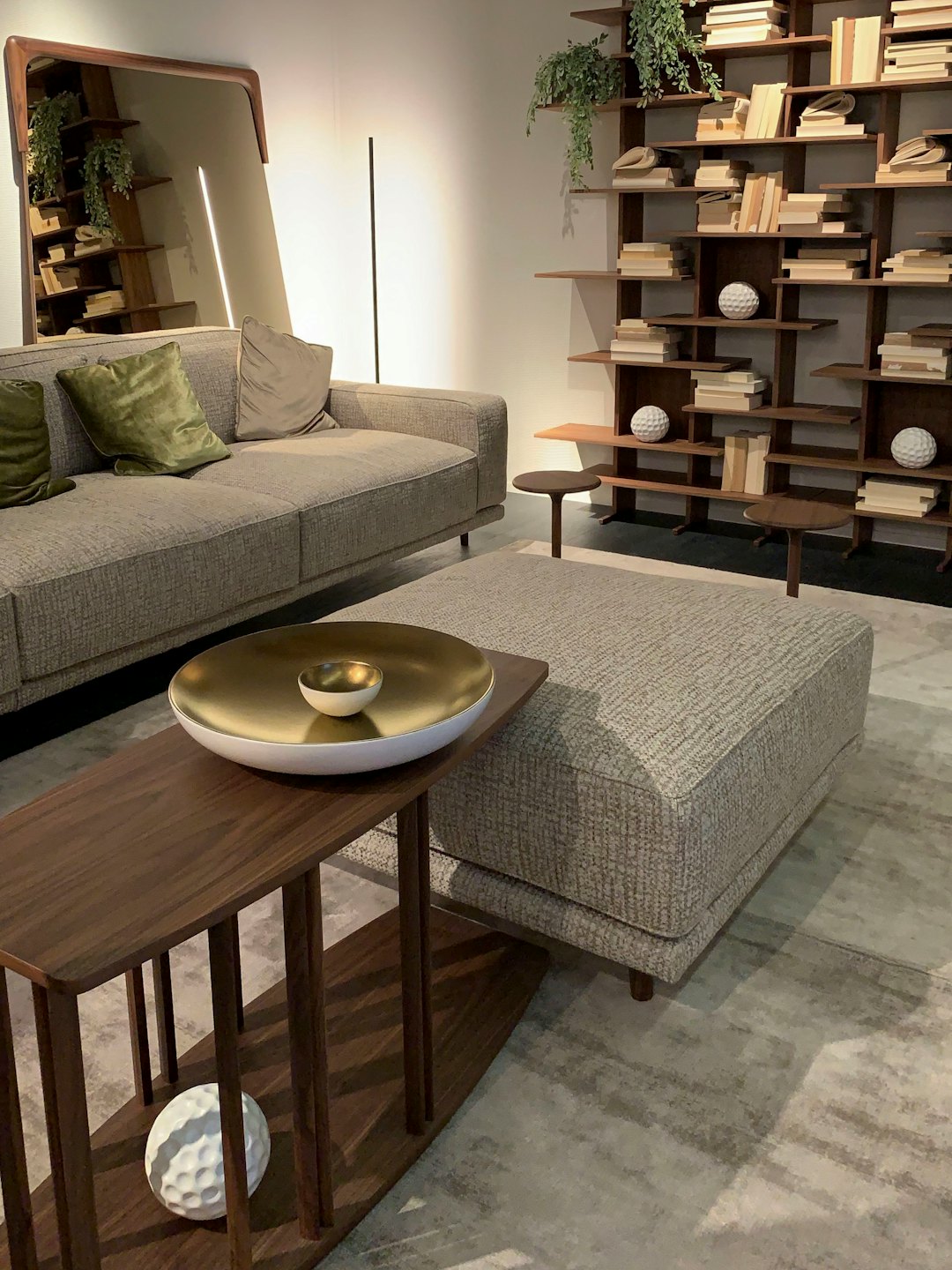 Salón moderno con sofá gris y estantería abstracta.
