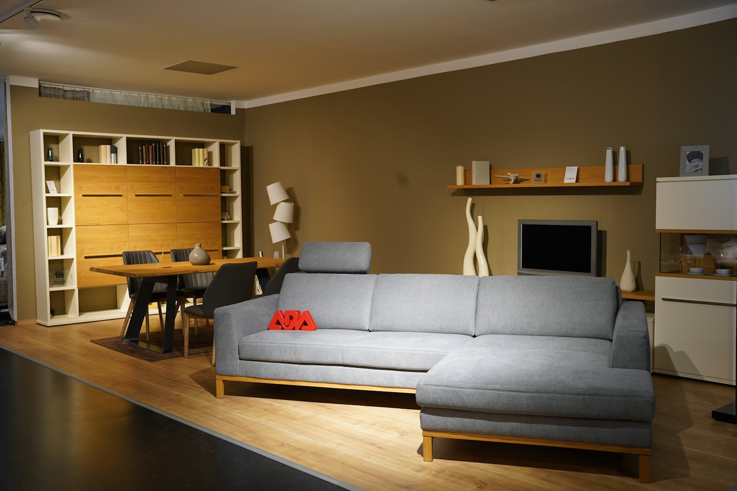 Sala de exposición de muebles modernos con sofá, mesa de comedor y estantería.